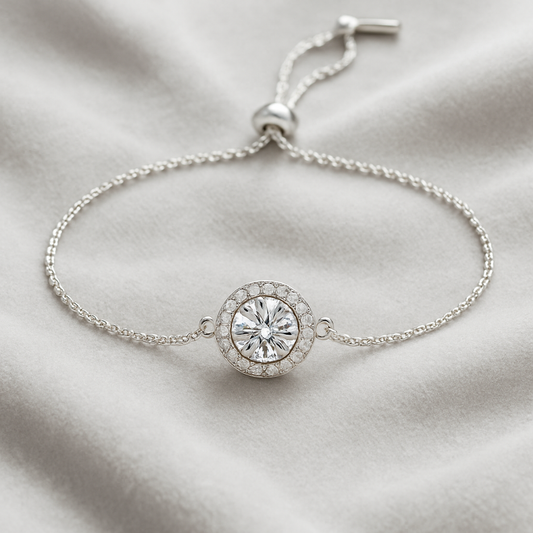 Silver bracelet with a round crystal charm on a light fabric background